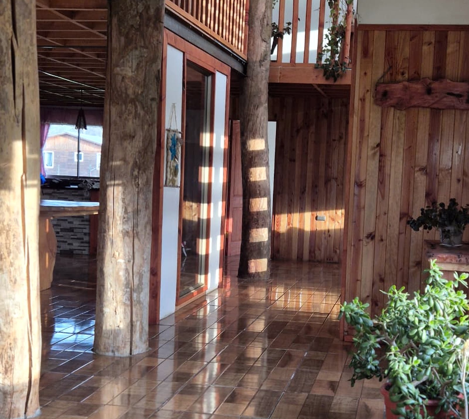 Interior de la casa de Centro Imperial, con columnas de troncos naturales y espacios comunes de madera